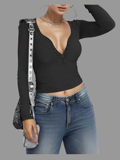 Person wearing a black long-sleeve top and blue jeans, holding a silver handbag.